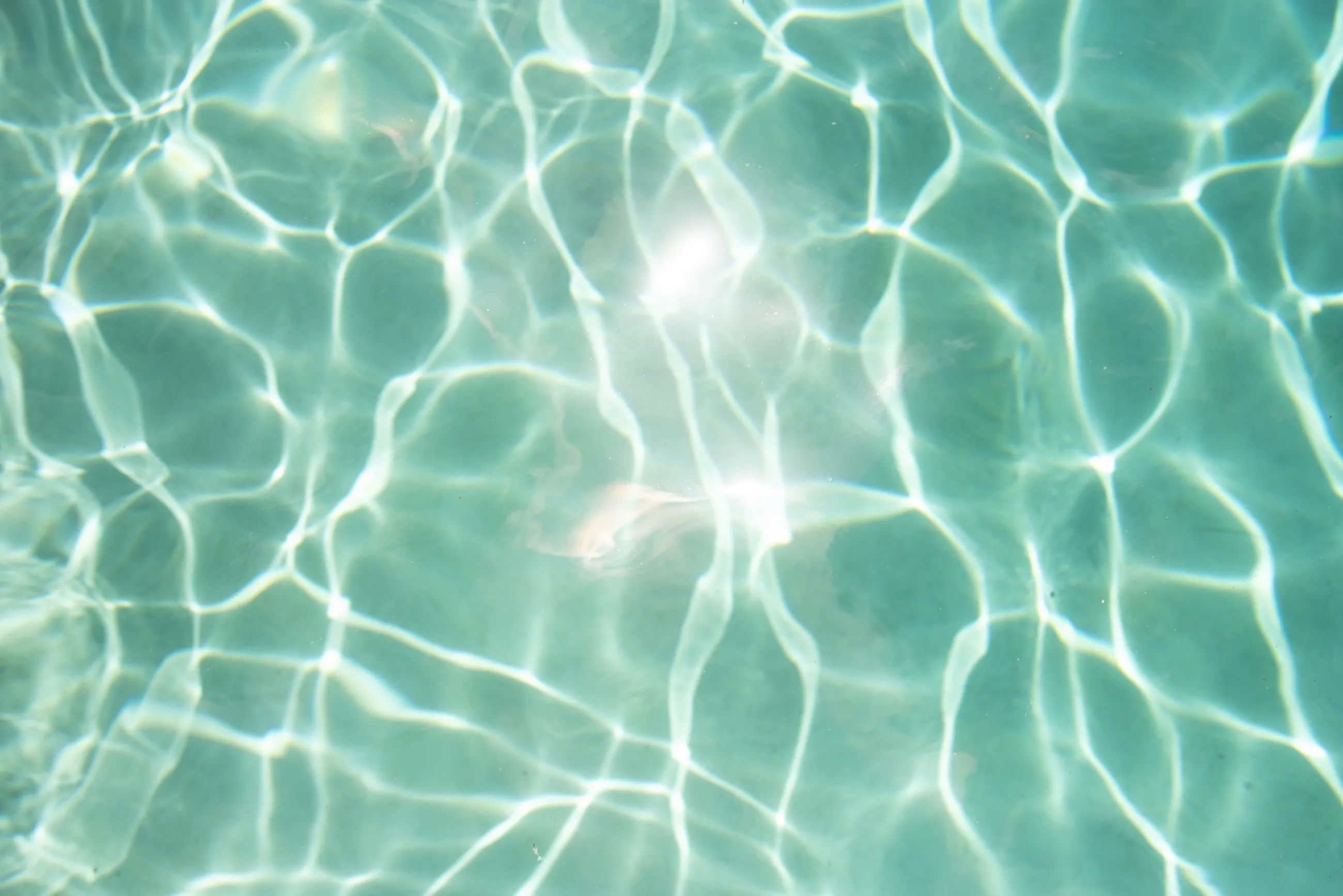 Superficie de agua de piscina turquesa con reflejos de luz solar